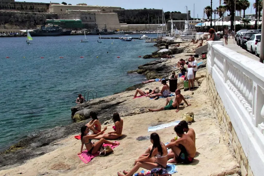 Menschen baden an der felsigen Küste von Ta’ Xbiex bei Gżira auf Malta